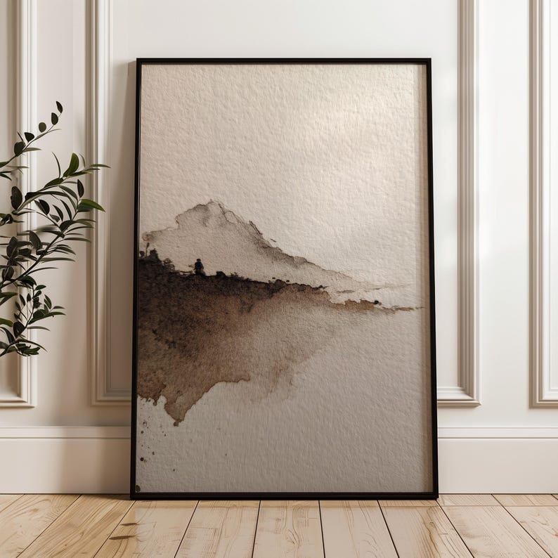 Abstract landscape art print in a minimal wabi-sabi style with earthy brown and beige watercolor tones on textured paper. The serene and calming design rests against a white paneled wall, perfect for minimalist or rustic interior decor. This peaceful wall art enhances the ambiance of a modern living space.