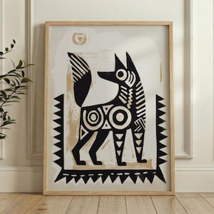 A man is holding a framed artwork of a stylized dog or fox, which is hanging on a wall.