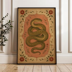 Op de afbeelding: Een ingelijste rechthoekige wandkunstprint met een opgerolde groene slang gecentreerd op een gedempte roze achtergrond. Het kunstwerk is omsloten door een decoratieve rand met bloemmotieven, waaronder rode bloemen en groene wijnranken.