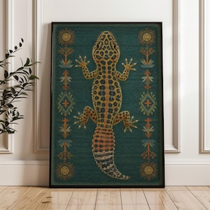 May include: A framed rectangular wall art print featuring a central yellow and black leopard gecko with a spotted pattern. The gecko is positioned vertically against a dark teal background, flanked by symmetrical orange and blue geometric motifs.