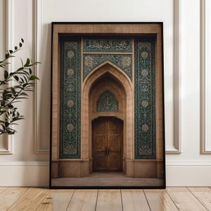 Peut inclure: Impression encadrée d'une porte ornée avec une porte en bois. L'arche est encadrée de carreaux turquoise et beiges avec des inscriptions arabes. La porte est en bois avec des sculptures complexes. L'impression est affichée sur un sol en bois.