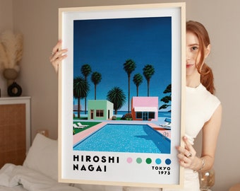 May include: A framed art print featuring a retro illustration of a swimming pool scene with palm trees, two colorful buildings, and the text "Hiroshi Nagai Tokyo 1973". The artwork has a light wood frame.