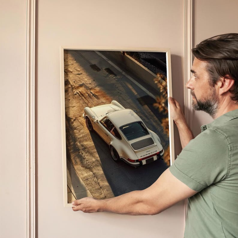 Vintage Porsche 911 captured in warm, golden-hour light highlighting its sleek, classic design. The automotive wall art print features nostalgic shadows and earthy tones for a timeless, retro car poster vibe. Displayed in a modern living room setting, it adds sophisticated car decor flair.