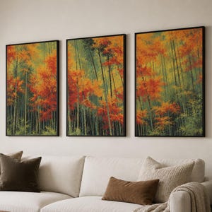 May include: A triptych of three rectangular wall art prints in black frames, each depicting a forest scene with tall, thin tree trunks and vibrant autumn foliage in shades of orange, red, yellow, and deep green, arranged horizontally on a wall.