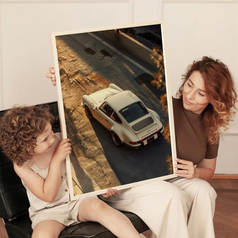 A vintage Porsche 911 captured in warm golden-hour light, highlighting its classic curves and timeless design. The photograph has a nostalgic, earthy tone perfect for automotive wall art. Displayed in a bright, modern living space, this classic car poster adds elegant car decor.