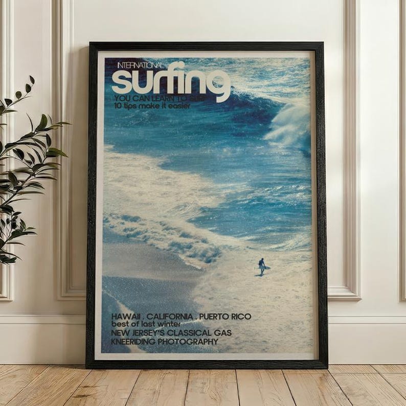 Vintage style surf poster featuring a lone surfer riding a large ocean wave in shades of blue and white. The nostalgic coastal print captures the energy and beauty of the sea with a retro magazine cover design. Displayed in a calm bedroom setting, it adds adventure and tranquility to beach-themed decor.