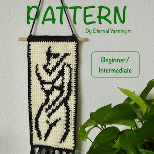 May include: A crochet pattern banner with the words "CROCHET PATTERN" in green. The banner is cream-colored with a black abstract design and a black border. The banner is hanging on a wall.