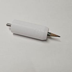 Könnte beinhalten: Ein weißer Bleistiftextender mit einer silbernen Spitze und einer Bleistiftmine aus Holz, die aus dem Ende herausragt.