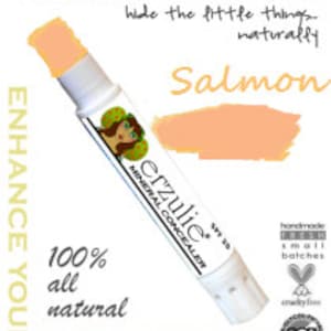 May include: A salmon-colored mineral concealer stick with the brand name "Derzulie" and the text "Mineral Corrector" and "Enhance Your Inner Goddess". The product is 100% all natural and handmade in small batches.