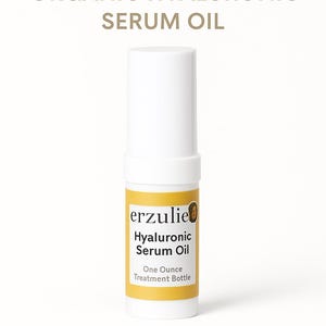 以下が含まれることがあります： 「erzulie Hyaluronic Serum Oil」と「One Ounce Treatment Bottle」と書かれた黄色のラベルが付いた白いボトルです。