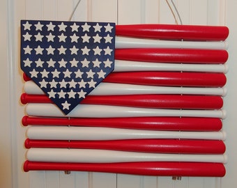 Könnte beinhalten: Eine handgefertigte amerikanische Flagge aus bemalten Holz-Baseballschlägern in Rot, Weiß und Blau. Die Flagge hat ein blaues Baseball-Homeplate mit weißen Sternen in der oberen linken Ecke.