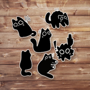 May include: Set of six black and white cat stickers with various expressions. The stickers feature a variety of cat poses, including a cat with its eyes wide open, a cat with its mouth open, and a cat with its tail curled up.
