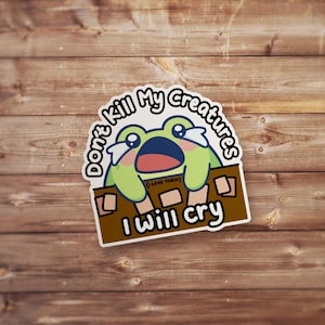 May include: A sticker featuring a cartoon frog with a sad expression, crying. The frog is green with a blue mouth and is holding onto a brown surface. Text on the sticker reads "Don't Kill My Creatures I Will Cry" with "(I Love Them)" below.