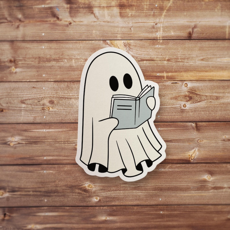 May include: A white ghost with two black eyes is reading a book. The ghost is wearing a white sheet and has a book in its hands. The book is open and has a gray cover.