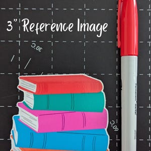 May include: A stack of colorful book stickers with red, green, pink, blue, and orange covers. A red and white permanent marker, approximately 6 inches long, is positioned next to the books. The text "3" Reference Image" is visible.