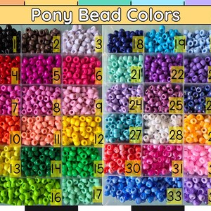 Puede incluir: Un organizador de pl&aacute;stico transparente lleno de cuentas de pony de varios colores. La parte superior del organizador tiene el texto "Pony Bead Colors". Cada compartimento est&aacute; etiquetado con un n&uacute;mero y contiene un color diferente de cuentas.