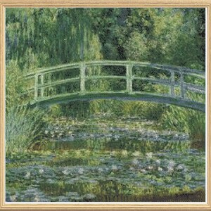 May include: A green wooden bridge spans a pond filled with water lilies. The bridge has a railing and is surrounded by lush green foliage.