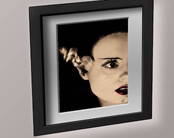 Può includere: Una fotografia in bianco e nero incorniciata di un viso di donna con un'acconciatura drammatica. La donna guarda a destra del telaio e indossa il rossetto rosso.
