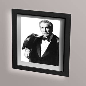 May include: Black and white photograph of a man in a tuxedo with a raven perched on his shoulder. The man is looking at the camera and the raven is looking away.