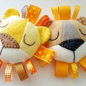 May include: Two plush lion head toys with yellow and orange ribbon tails. The lions have closed eyes and are made of felt.