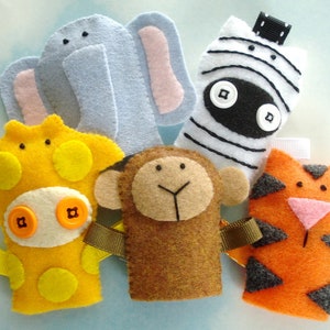 May include: Five felt finger puppets, each depicting a different animal: a yellow giraffe, a brown monkey, a gray elephant, a black and white zebra, and an orange tiger. The puppets have button eyes and are decorated with simple details.