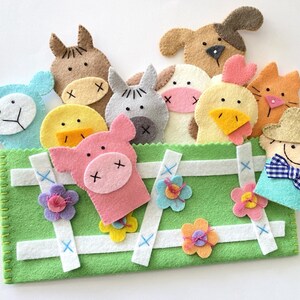 May include: A green felt puppet theater with a white picket fence design. The theater includes felt finger puppets of a pig, a cow, a chicken, a sheep, a horse, a cat, a dog, and a farmer.
