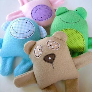 May include: Four plush toys: a pink pig, a blue monkey, a green frog, and a brown bear. The toys have embroidered faces and are made of soft fabric.