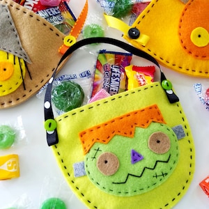 May include: Three felt Halloween trick-or-treat bags with different character designs. The bags are filled with sweets and have black ribbon handles. The characters are a scarecrow, a pumpkin, and a Frankenstein.