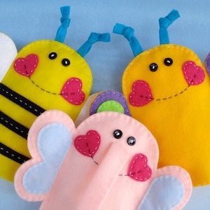 May include: Three felt finger puppets: a yellow bee with black stripes, a yellow butterfly with purple and green wings, and a pink elephant with blue wings.