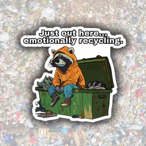 May include: A sticker featuring a raccoon wearing an orange hoodie and blue jeans, sitting on a green dumpster. The text reads, "Just out here... emotionally recycling."
