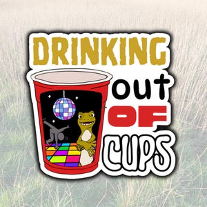 May include: A sticker featuring a red cup design with the words "DRINKING OUT OF CUPS" in gold and white. Inside the cup is a disco scene with a lizard and a breakdancer.