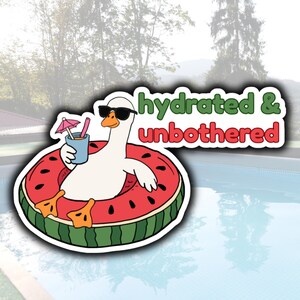 May include: A sticker featuring a cartoon goose wearing sunglasses and floating in a watermelon-shaped pool float. The goose holds a drink with a pink umbrella. Text reads "hydrated & unbothered". The background shows a pool and trees.