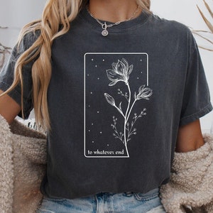 May include: A dark gray t-shirt with a white graphic of a flower with the text "to whatever end" printed on the front.
