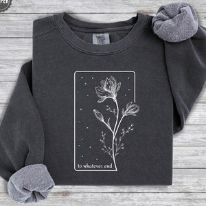 May include: A charcoal gray sweatshirt with a white graphic of a flower with the text "to whatever end" printed below it.