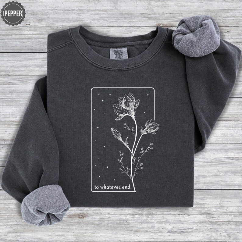 May include: A charcoal gray sweatshirt with a white graphic of a flower with the text "to whatever end" printed below it.