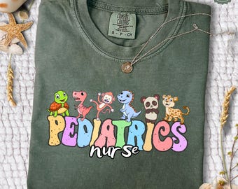 May include: A green t-shirt with the words "PEDIATRICS nurse" in rainbow colors.  The words are surrounded by cartoon animals including a turtle, dinosaur, monkey, dragon, panda, and cheetah.