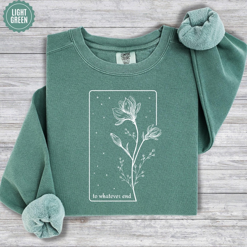 May include: A light green sweatshirt with a white graphic of a flower and the text "to whatever end".