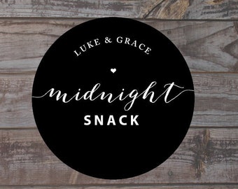 May include: A black circular design with the words "Luke & Grace" above a heart and the word "midnight" in cursive, with "SNACK" below. The design is on a wooden background. The words "Anna Malie Design" are at the bottom left.