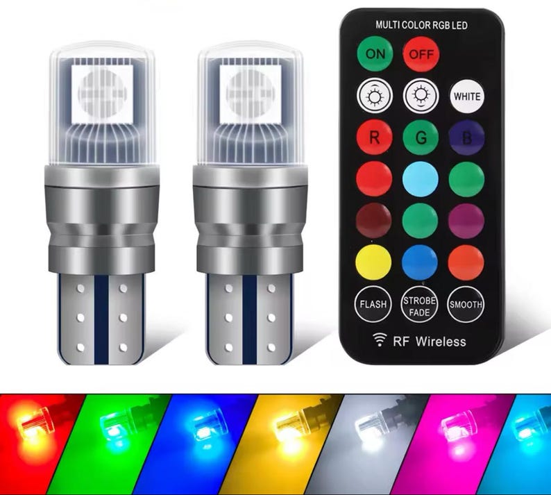 Op de afbeelding: Twee witte LED-lampjes met een zilveren basis en een afstandsbediening met 16 knoppen om de kleur van de lampjes te veranderen. De afstandsbediening heeft de tekst "MULTI COLOR RGB LED", "ON", "OFF", "WHITE", "R", "G", "B", "FLASH", "STROBE FADE", "SMOOTH" en "RF Wireless".