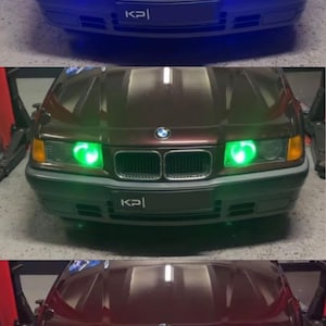 Op de afbeelding: Een donkerrode BMW met een zwart kenteken waarop "KPI" staat. De auto heeft drie verschillende gekleurde koplampen: blauw, groen en rood.