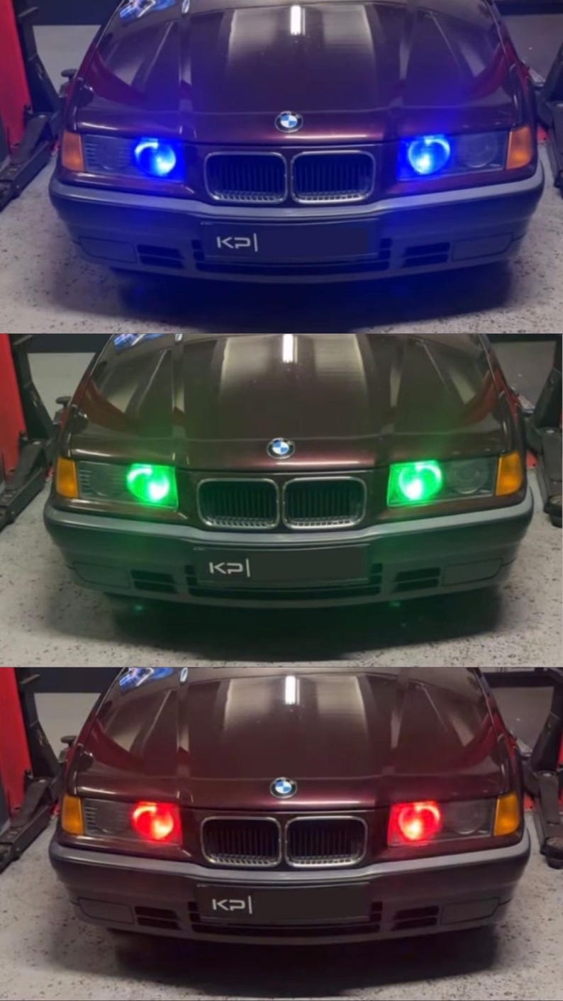 Op de afbeelding: Een donkerrode BMW met een zwart kenteken waarop "KPI" staat. De auto heeft drie verschillende gekleurde koplampen: blauw, groen en rood.