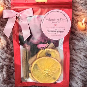 Pu&ograve; includere: Un sacchetto di cellophane rosso legato con un fiocco rosa, contenente un pot-pourri per la cottura a fuoco lento di San Valentino. La borsa include fette d'arancia essiccate, bastoncini di cannella e petali di rosa. Il testo sull'etichetta recita "Valentine's Day Simmer Pot".