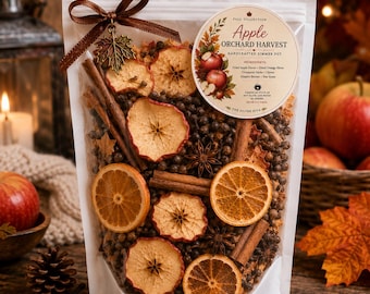 May include: A clear pouch containing a potpourri mix of dried apple slices, orange slices, cinnamon sticks, star anise, and cloves. A brown ribbon with a metal maple leaf charm is tied at the top. A circular label reads Apple Orchard Harvest.