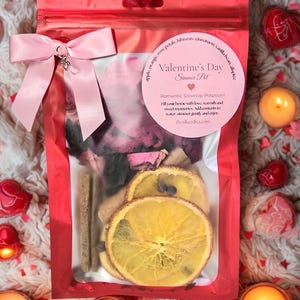 Pu&ograve; includere: Un sacchetto rosa di cellophane legato con un fiocco rosa, contenente pot-pourri per San Valentino. La borsa include fette d'arancia essiccate, bastoncini di cannella e petali di rosa. L'etichetta recita "Valentine's Day Simmer Pot".