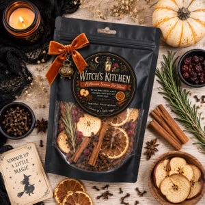 Pu&ograve; includere: Una busta nera di miscela per infusione Witch's Kitchen Halloween con una finestra trasparente che mostra fette di mela e arancia essiccate, bastoncini di cannella e anice stellato, decorata con un fiocco in velluto arancione bruciato.