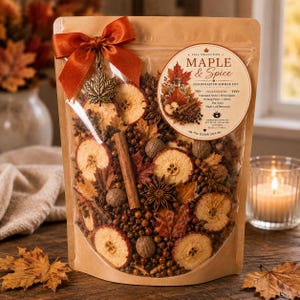 May include: A clear pouch filled with dried apple slices, cinnamon sticks, star anise, whole nuts, and autumn leaves. The bag features a rust-colored ribbon, a metal maple leaf charm, and a label reading Maple & Spice Handcrafted Simmer Pot.