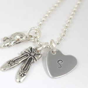 May include: Silver necklace with a heart charm engraved with the letter "S", a pair of ballet shoe charms, and a mouse charm.