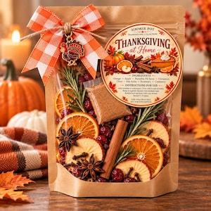 May include: A brown paper pouch containing dried orange slices, cinnamon sticks, star anise, rosemary, cranberries, and a small packet of spice. It features an orange and white gingham bow with a turkey charm and a label reading Thanksgiving at Home.