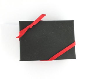 May include: A black gift box with a red ribbon tied around it.
