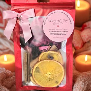 Pu&ograve; includere: Un sacchetto di cellophane rosso pieno di pot-pourri, legato con un fiocco rosa. La busta contiene fette d'arancia essiccate, bastoncini di cannella e petali di rosa. Un'etichetta rosa recita "Valentine's Day Simmer Pot".